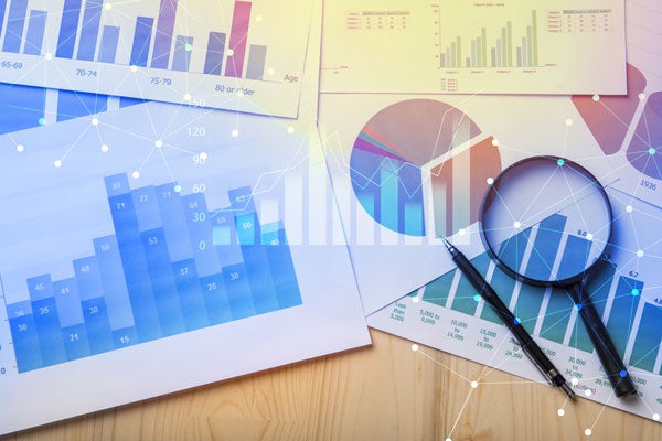 magnifying glass on top of colorful reports and charts